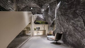 Un interior moderno con una pared de piedra, un escritorio con computadora y una silla.