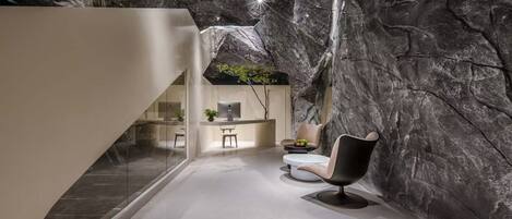 A modern interior with a stone wall, a desk with a computer, and a chair.