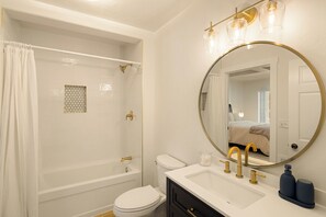 A bathroom with a bathtub, toilet, sink, and a large mirror. - River's Rest: 3BR, waterfront views, hot tub, grill, fire pit! (Walterville)