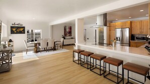 Une cuisine moderne dotée d’un îlot central, de tabourets de bar et d’un coin repas avec une table et des chaises.