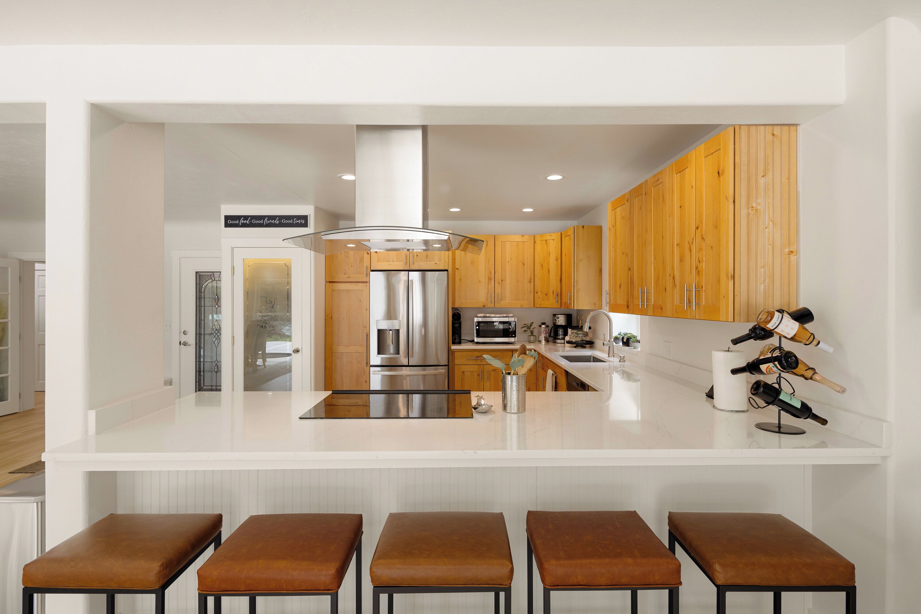 A modern kitchen with wooden cabinets, stainless steel appliances, and a central island with bar stools.