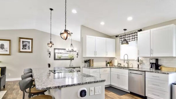 A modern kitchen with white cabinets, granite countertops, and a central island with bar stools.