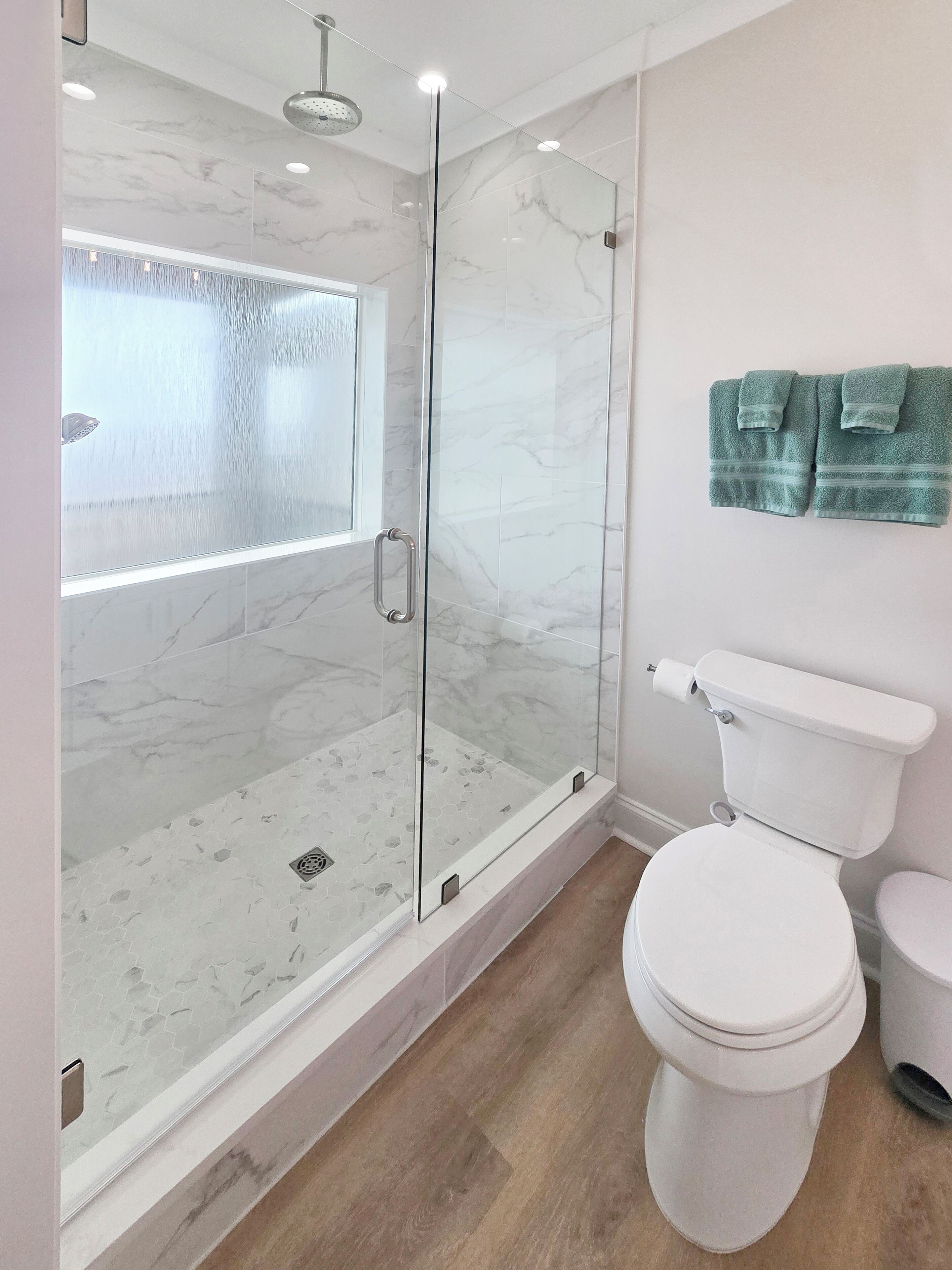 Un baño moderno con ducha envuelta en vidrio, inodoro y lavamanos.