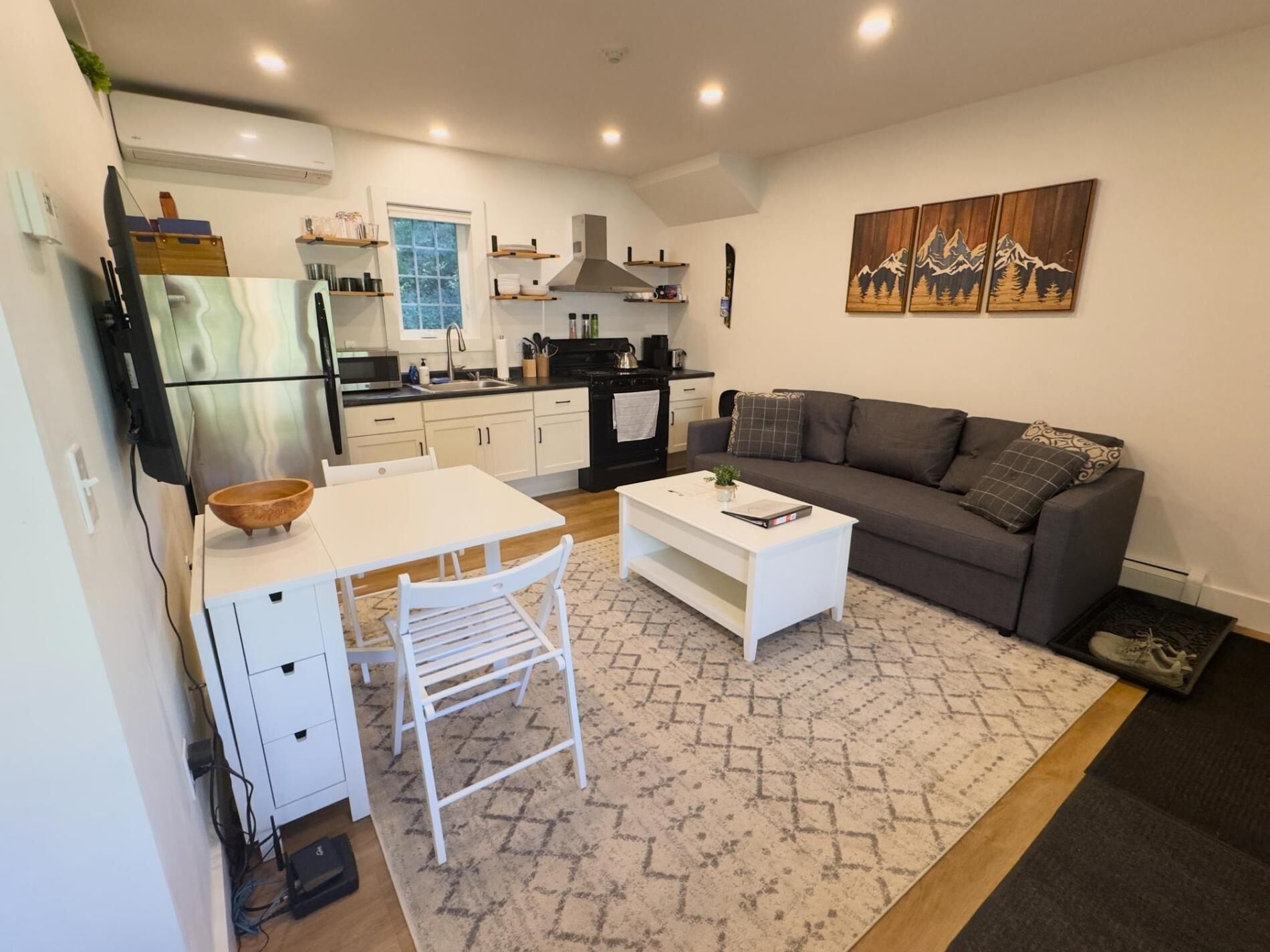 A compact living space with a kitchenette, a dining area, and a seating area with a sofa and coffee table.