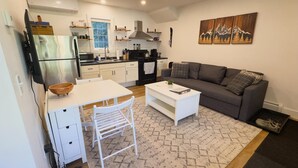 Ein gemütlicher Wohnraum mit Küchenzeile, Essbereich und einer Sitzecke mit Sofa und Couchtisch.