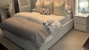 Un dormitorio con una cama grande, una mesita de noche con lámpara, un candelabro en el techo y una decoración de cráneo de vaca colgado en la pared.