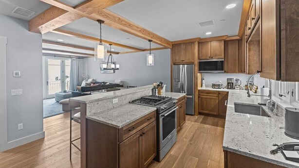 A modern kitchen with wooden cabinets, granite countertops, and stainless steel appliances.