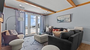 A spacious living room with a large window, a sofa set, a coffee table, and a floor lamp.