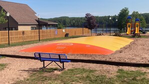 Un parque infantil con un arenero, un banco y una valla de madera.
