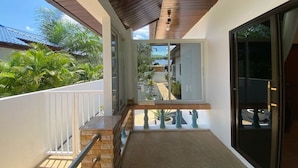 A balcony with a view of a residential area, a wooden ceiling, and a glass door leading to a patio.