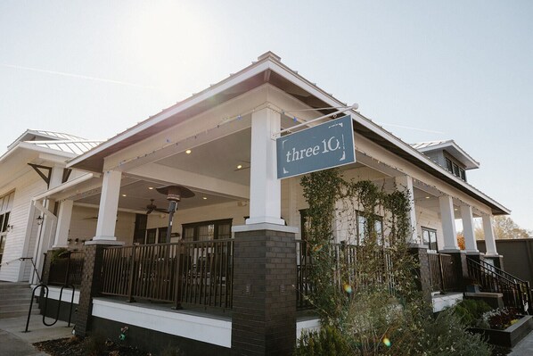 A two-story building with a covered porch and a sign reading "three 10".