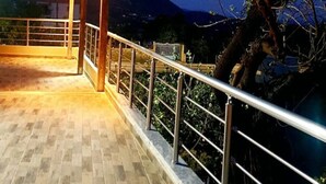 Un espace extérieur abrité, doté d’une pergola en bois et d’une rambarde en métal, offrant une vue sur un paysage montagneux.