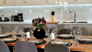 Une cuisine moderne dotée d’un plan de travail en marbre, d’un évier et d’un coin repas agrémenté d’assiettes, de verres et d’un centre de table.
