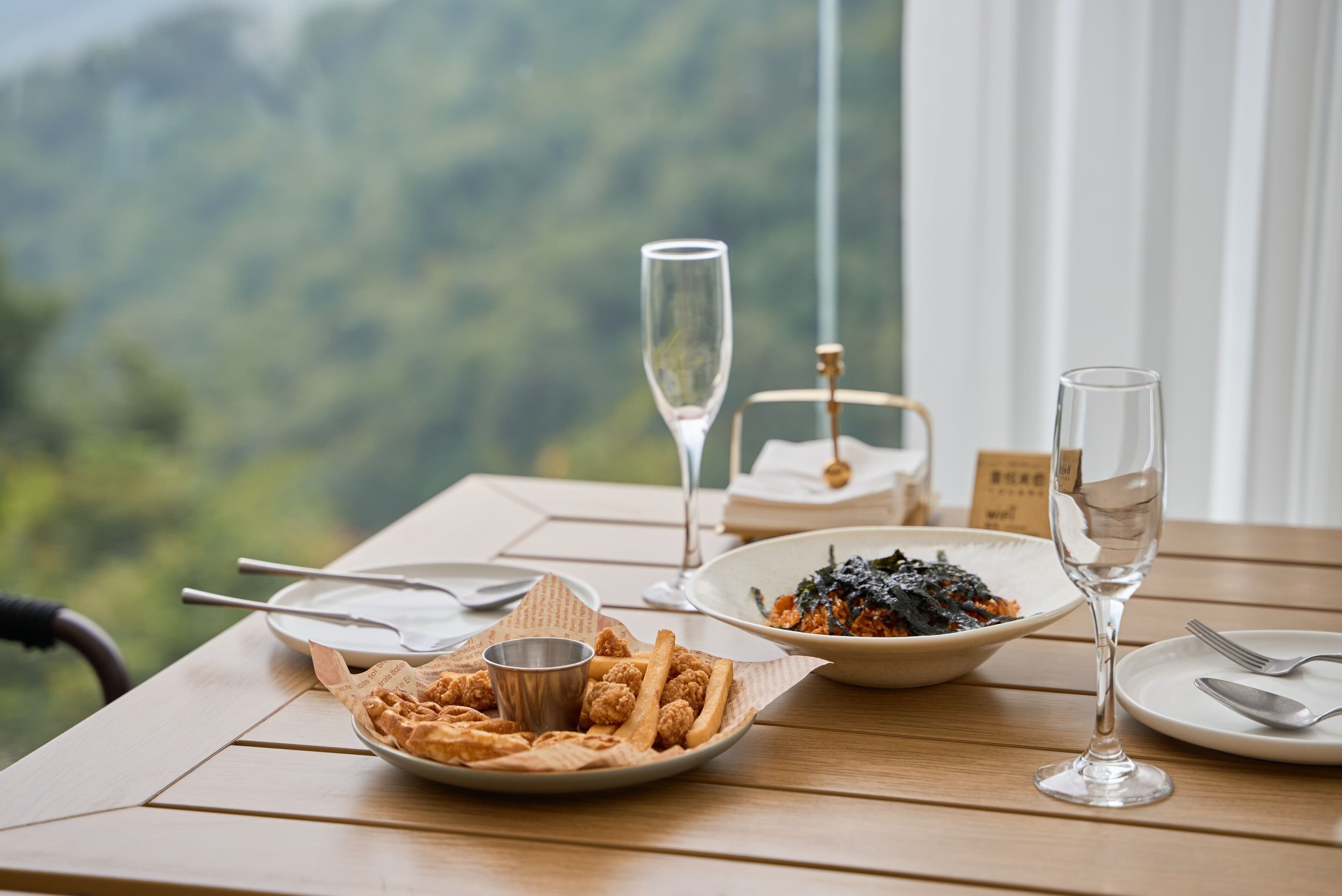 A table with a plate of tater tots, a bowl of pasta, and a glass of water.