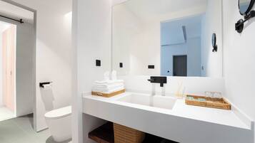 A modern bathroom with a white sink, a large mirror, and a toilet.