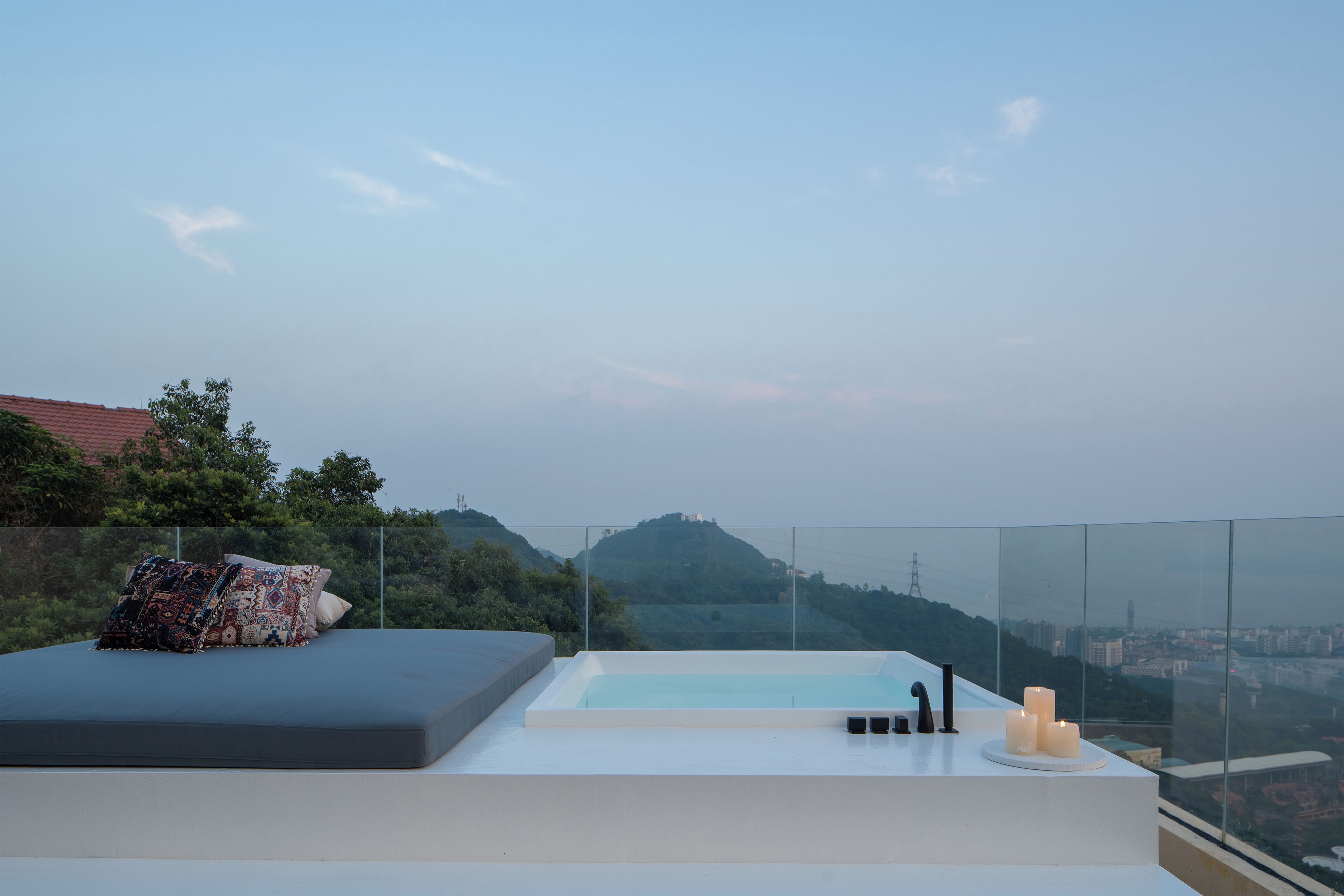 Une terrasse sur le toit équipée d’un lit, d’un jacuzzi et offrant une vue sur le paysage urbain.