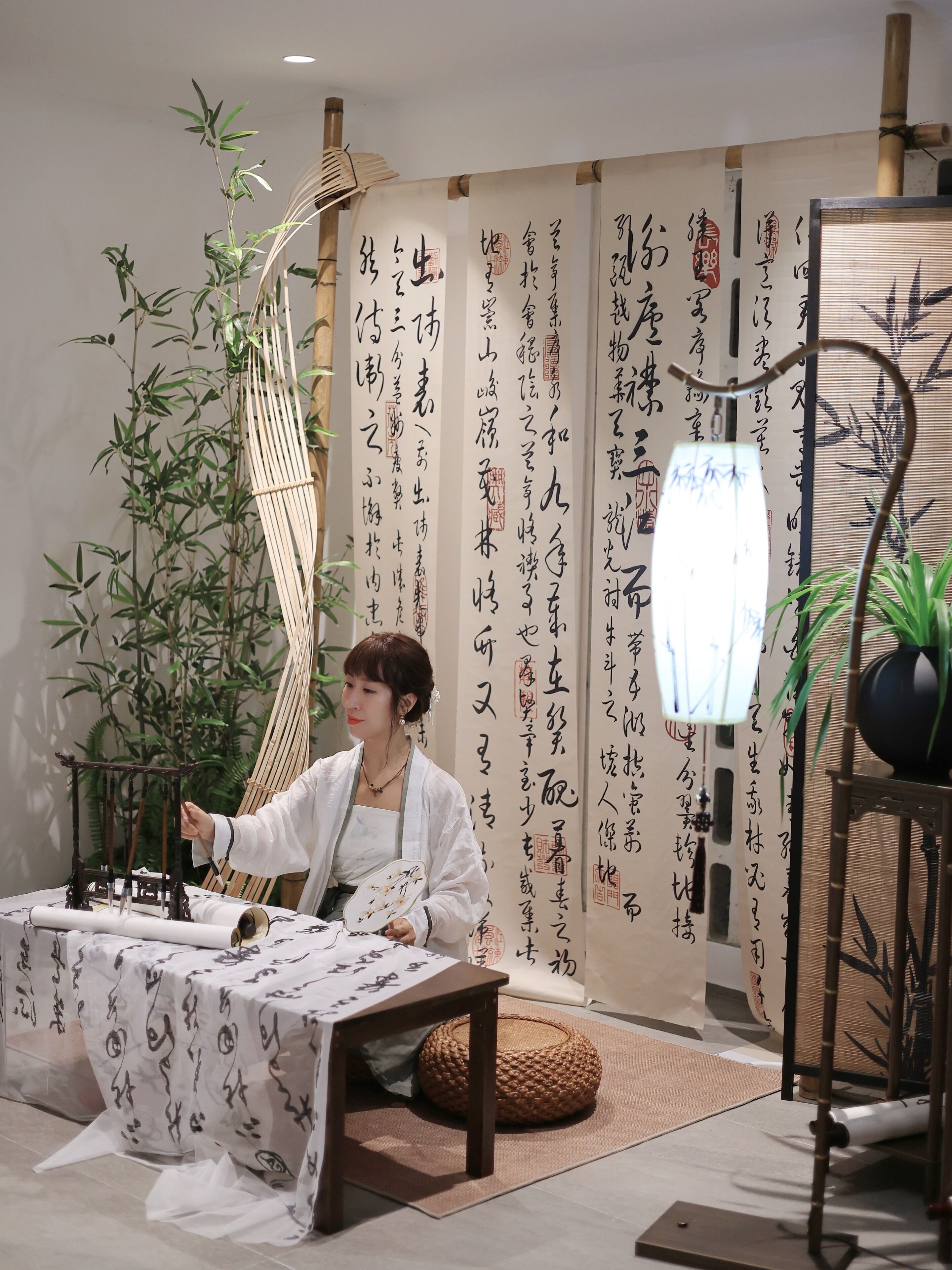 A room with a traditional Japanese aesthetic, featuring a tatami mat floor, a low table with a decorative item, and a hanging scroll with calligraphy.