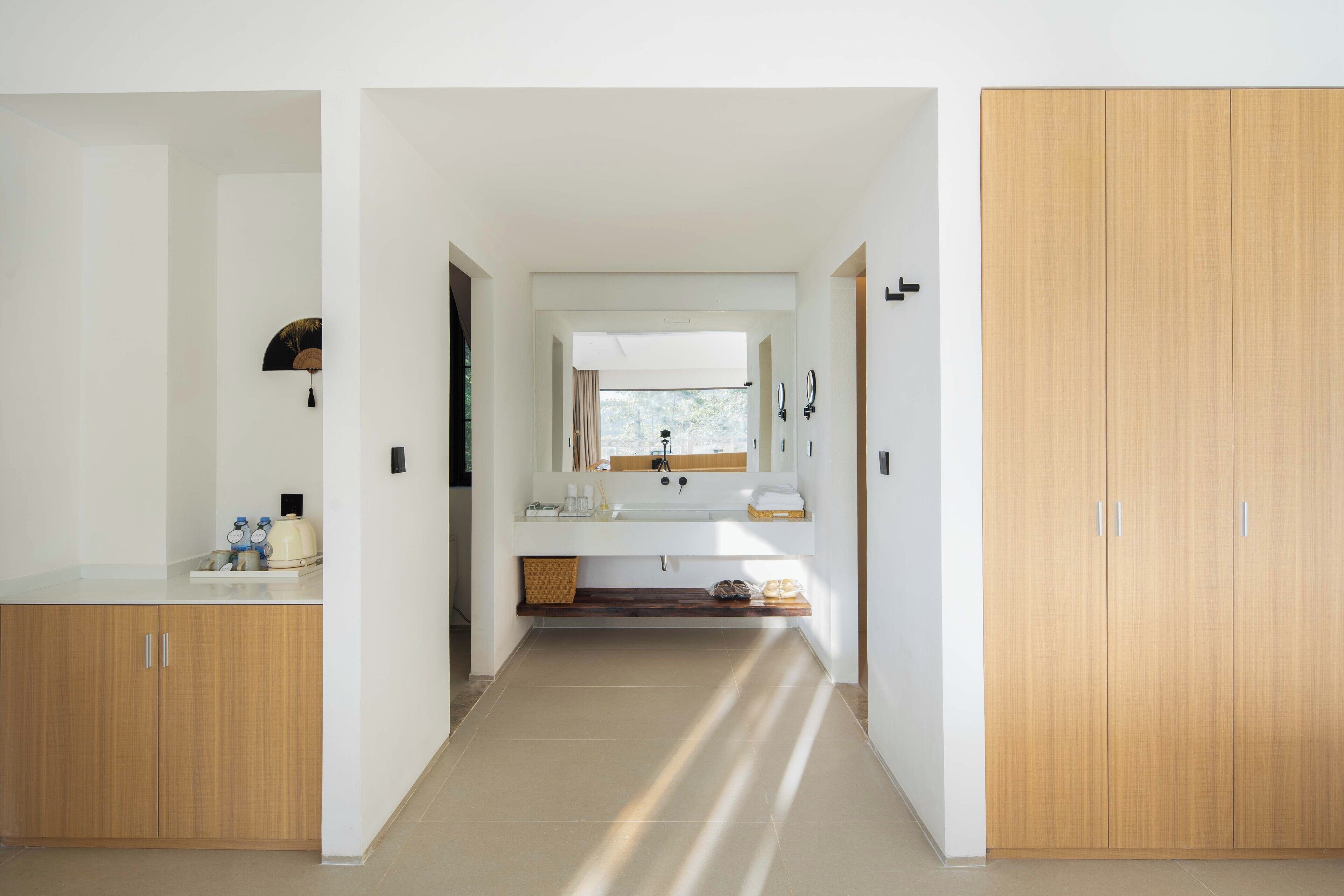 A modern bathroom with a large mirror, a sink, and a wooden wardrobe.