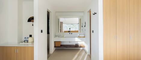 A modern bathroom with a large mirror, a sink, and a wooden wardrobe.