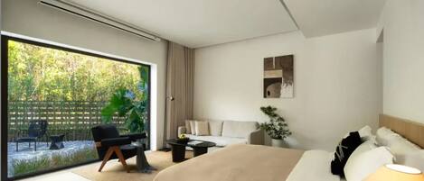 Ein modernes Hotelzimmer mit einer großen Glasschiebetür, die zu einem Garten führt, einem Bett mit beiger Bettdecke, einem kleinen runden Tisch, einer Couch und einer Topfpflanze.