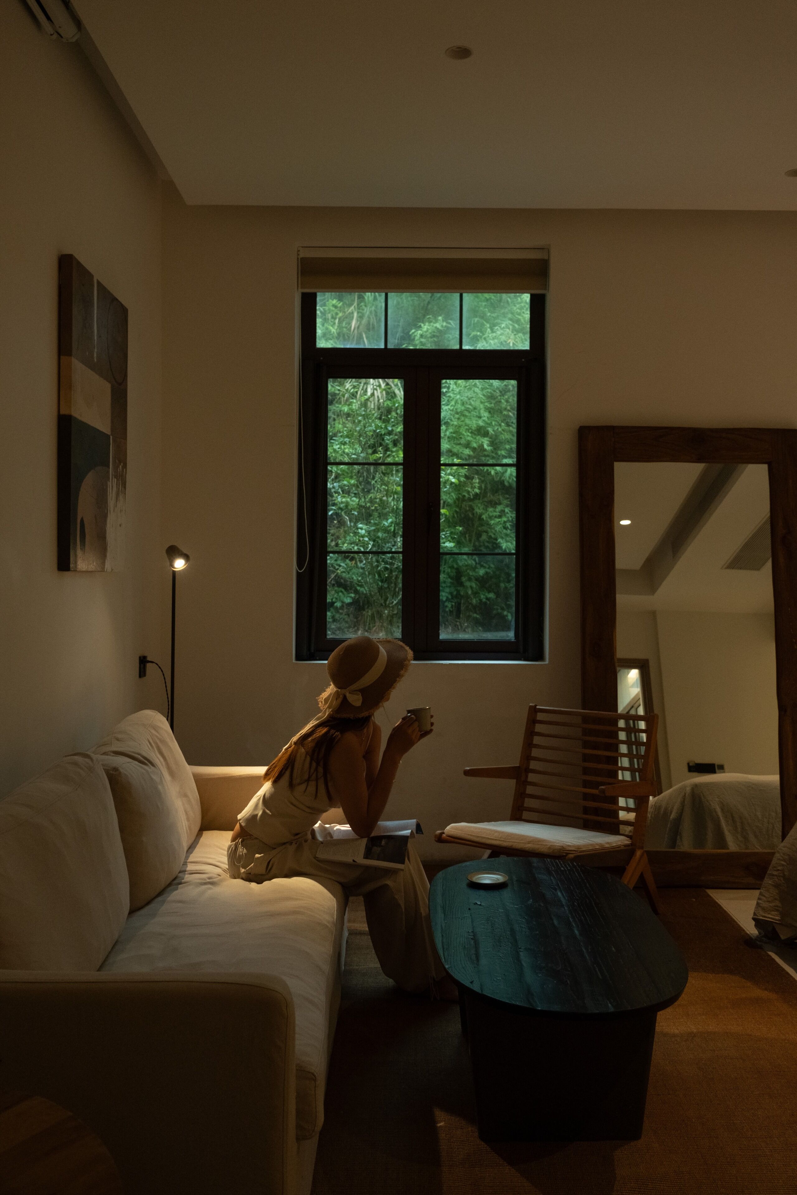 Una habitación acogedora con un ventanal grande, una silla de madera, una mesita pequeña y un sofá.
