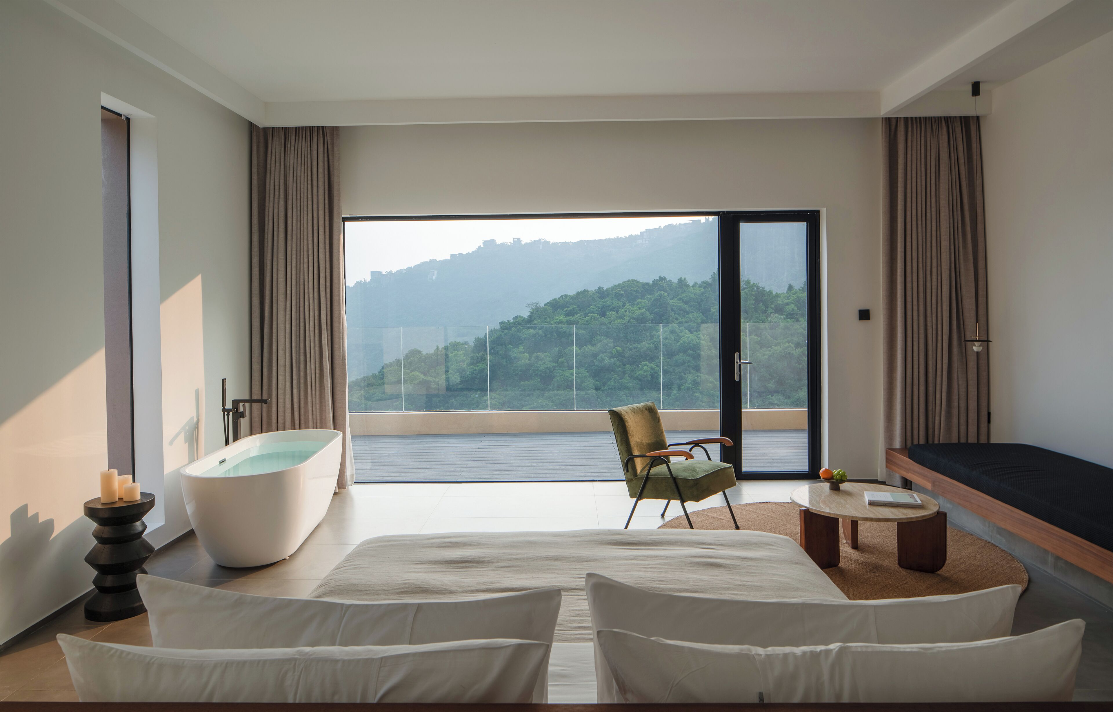 Un dormitorio moderno con una cama grande, una bañera, una silla y vistas a un paisaje montañoso.