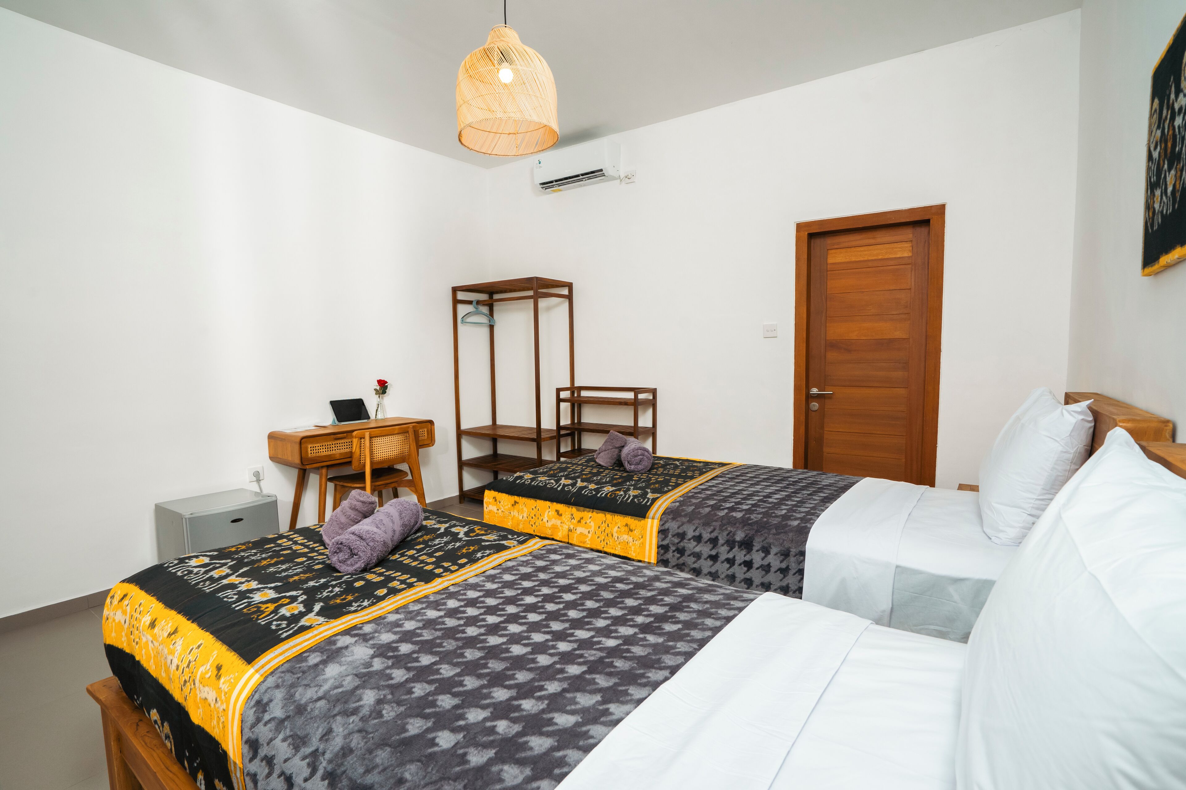 Une chambre d’hôtel avec deux lits, un bureau, une chaise et une porte.