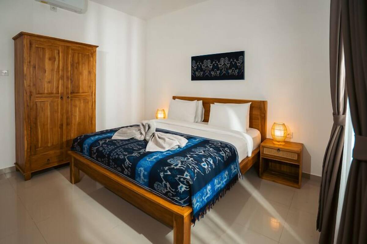 A bedroom with a wooden bed, a wardrobe, and a nightstand with a lamp.
