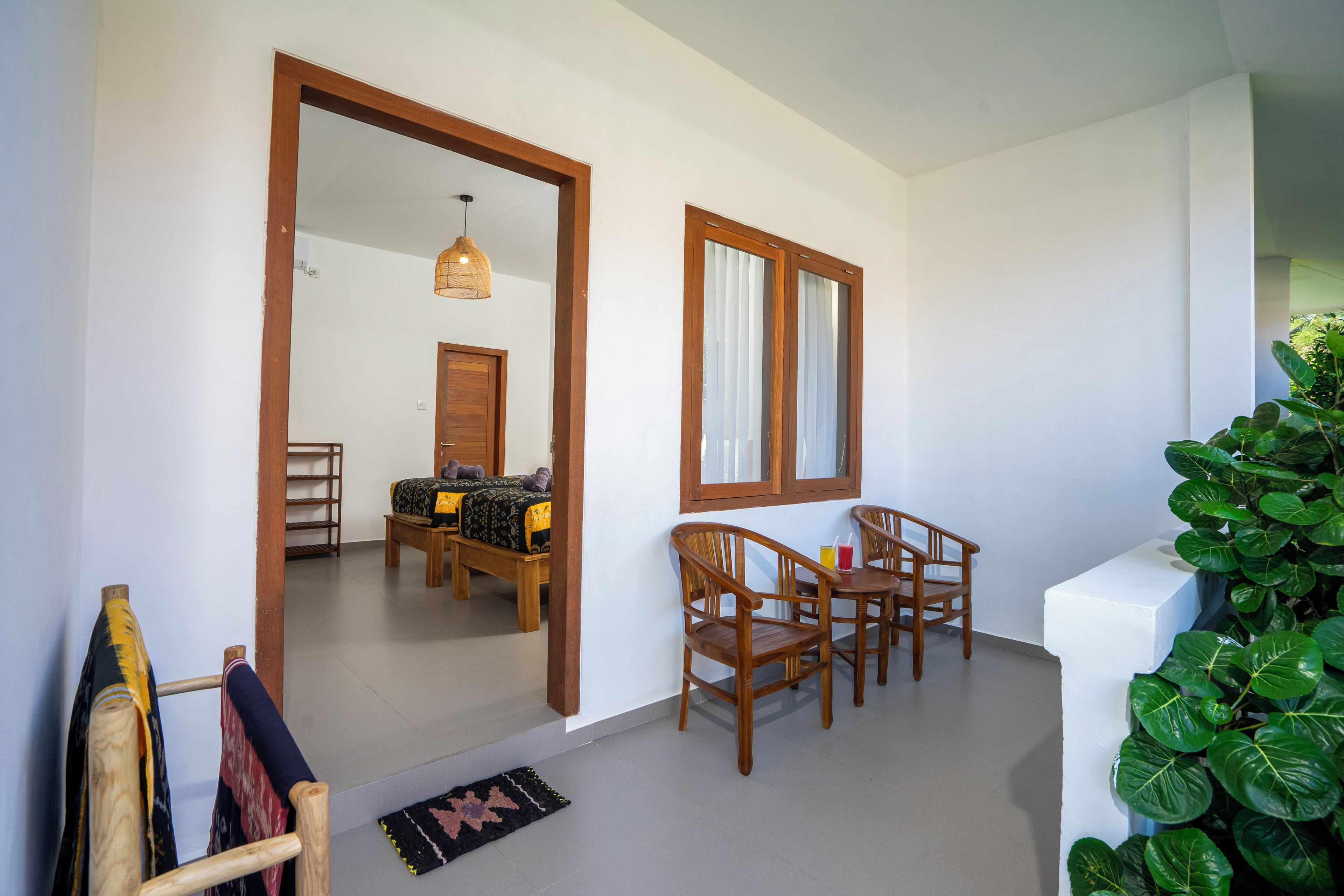 Una habitación con cama de madera, una mesa de comedor con sillas, una pequeña cocina y un ventanal grande.