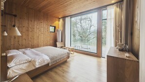 Een kamer met houten vloer, een bed, een tafel en een groot raam.