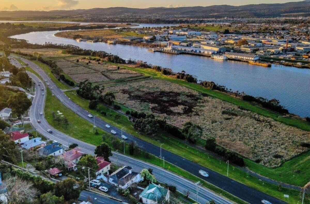 Luftaufnahme einer Flussstadt mit Autobahn, Wohngebieten und Industriegebäuden.