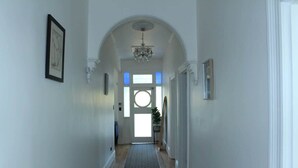 A hallway with a patterned rug, a chandelier, and framed artwork on the walls. - Forest Rd Haven with Tamar River Views (Trevallyn)