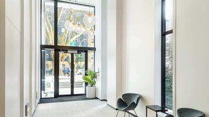 A modern lobby with a glass door entrance, a potted plant, and two black chairs. - Cozy Aircon Studio Nearby Skytower -Pool Sauna Gym (Auckland)