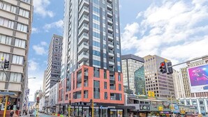 A city street with tall buildings, including a prominent red and black building. - Prime Location 1BR vs Aricon&Pool beside Skytower (Auckland)