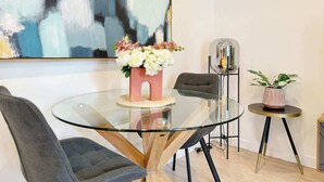 A modern dining area with a glass table, chairs, a pink flower vase, and a large abstract painting on the wall. - Prime Location 1BR vs Aricon&Pool beside Skytower (Auckland)