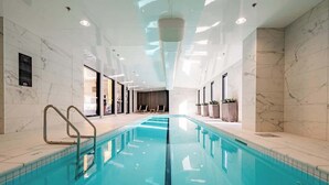 An indoor swimming pool with clear water, marble walls, and a modern ceiling design. - Incredible View Aircon 1B Studio Auckland Central (Auckland)