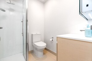 A modern bathroom with a glass shower enclosure, a toilet, and a sink with toiletries. - Incredible View Aircon 1B Studio Auckland Central (Auckland)