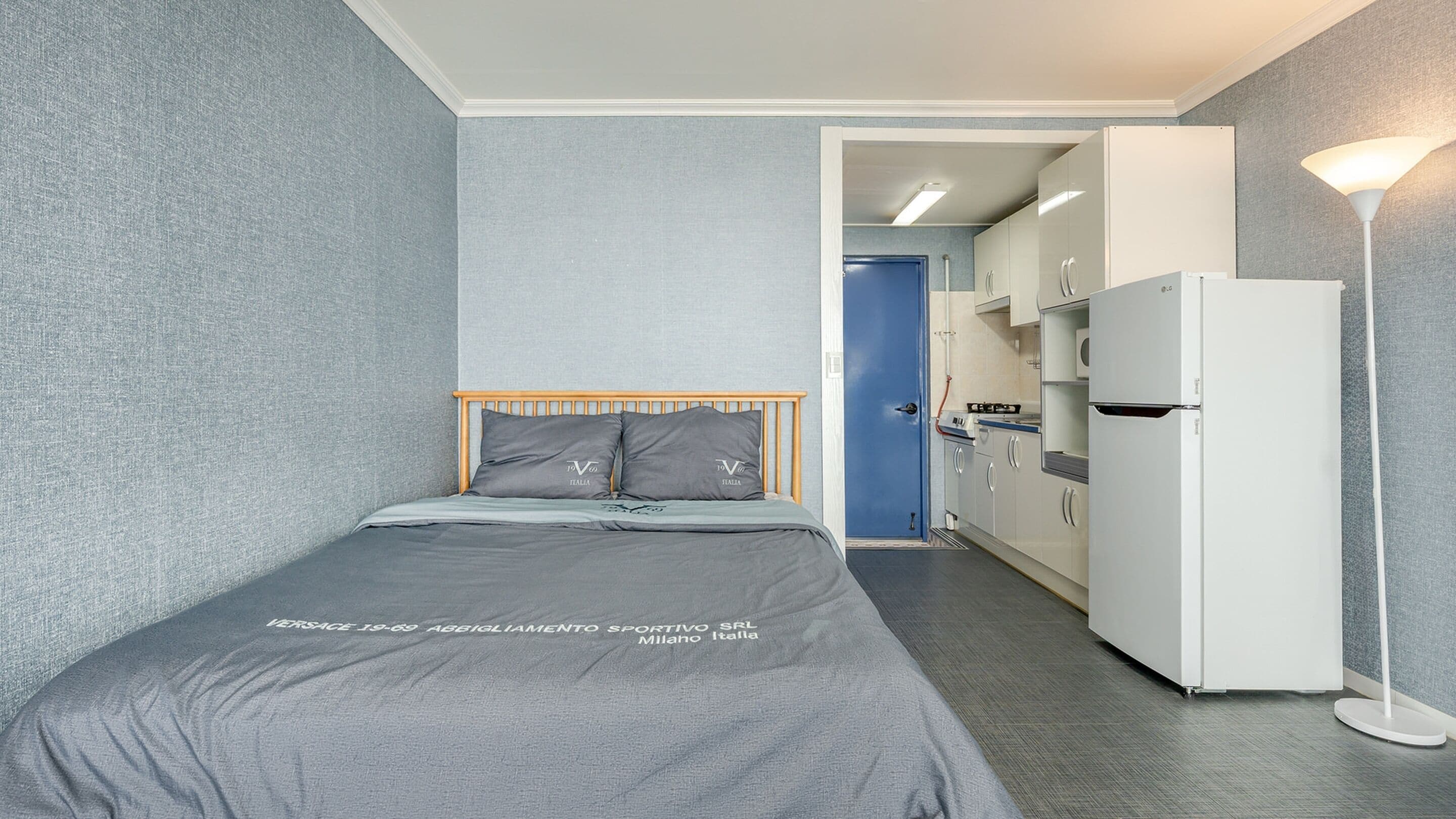 Une chambre d’hôtel compacte comprenant un lit, une kitchenette et un dressing.