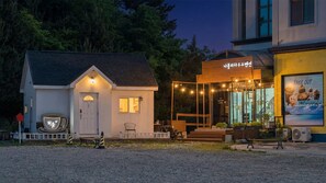 A small building with a white exterior, a porch with chairs, and a sign above the entrance. - Goseong Napoli House Pension (Goseong)