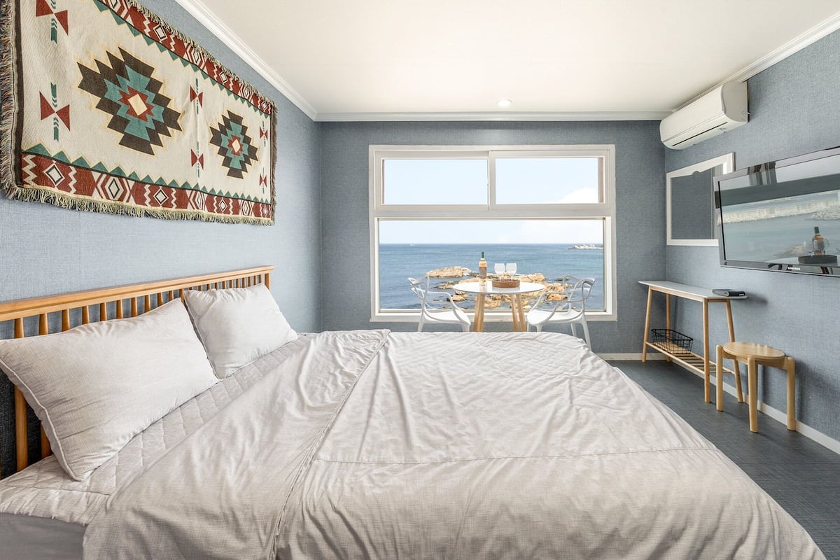 Un dormitorio con una cama grande, televisión, escritorio y vista al mar.