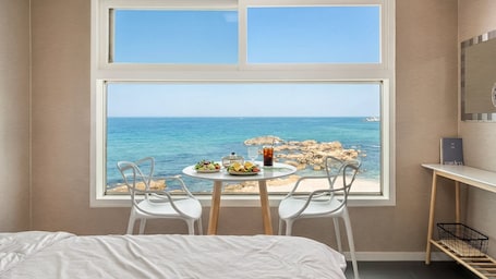 A bedroom with a large window, a bed, a small table with food, two chairs, and a nightstand.. Goseong Napoli House Pension