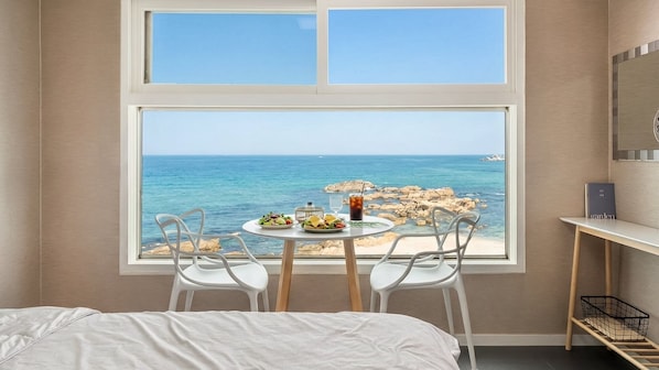 A bedroom with a large window, a bed, a small table with food, two chairs, and a nightstand. - Goseong Napoli House Pension (Goseong)