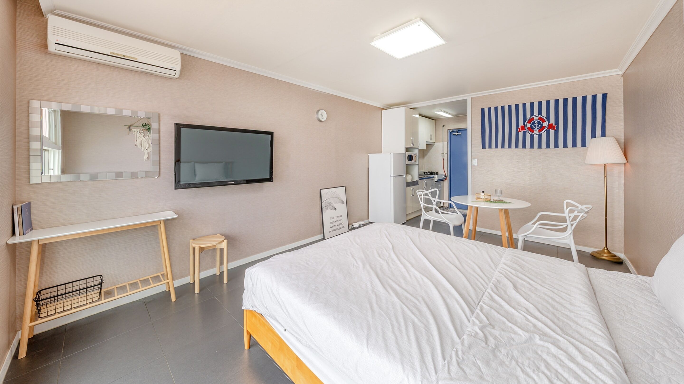 Ein Hotelzimmer mit Bett, Fernseher, Schreibtisch, Stuhl, kleinem Tisch und Spiegel.