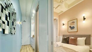 A modern bedroom with a large bed, a bedside table, and a wall-mounted light fixture.