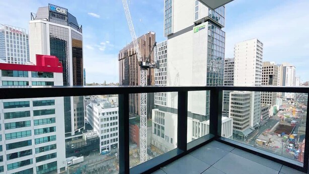 Een hoog gebouw met uitzicht op de stadsgezicht, inclusief andere gebouwen en een hijskraan.