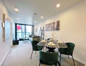 Uma área de jantar moderna com uma mesa redonda, cadeiras verdes e toalha de mesa xadrez.