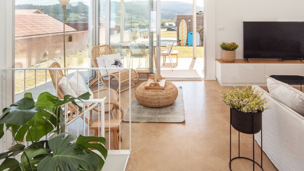 A modern living room with a balcony, large windows, and a flat-screen TV. - AG Villa Razo Deluxe, with swimming pool and beach 400m away (Razo Da Costa)