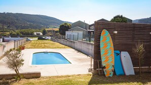 A backyard with a swimming pool, a wooden fence, and surfboards leaning against it. - AG Villa Razo Deluxe, with swimming pool and beach 400m away (Razo Da Costa)