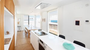 A modern kitchen with a white countertop, a sink, and a view of the sea through large windows. - AG Villa Razo Deluxe, with swimming pool and beach 400m away (Razo Da Costa)