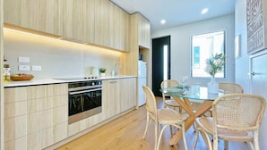 Una cocina moderna con armarios de madera, una mesa de comedor de vidrio y sillas de mimbre.
